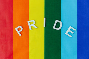 A rainbow pride flag background that reads "Pride" in white, all-caps letters